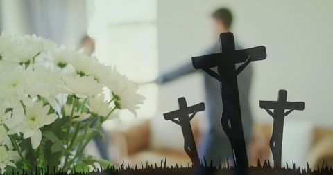 White chrysanthemum bouquet with triple cross silhouettes and blurred couple in mourning
