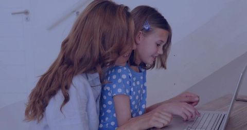 Mother guiding daughter using laptop, teaching typing skills, home learning and bonding