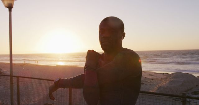 Man stretching muscles near beach during sunset, ideal for fitness, motivation, wellness, and travel themes. Promotes healthy and active lifestyle, emphasizing the benefits of outdoor workouts. Useful for blogs, websites, advertisements, and social media.