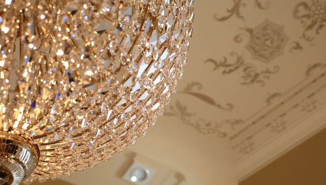 Glittering crystal chandelier casting golden sparkle against ornate plaster ceiling