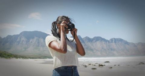 Woman Capturing Scenic Coastal Mountain Views with Camera
