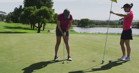 Women Golfers Putting on Scenic Course Near Lake