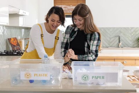 Women sorting recyclables at kitchen island promoting sustainable living and home recycling