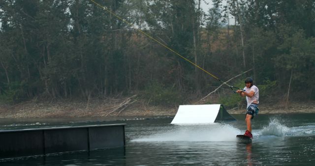 Man Wakeboarding in Lake with Forest Background - Download Free Stock Images Pikwizard.com