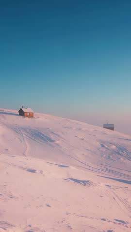 Sun Rising, Camera Panning Across Snowy Alpine Slope Revealing Two Remote Cabins