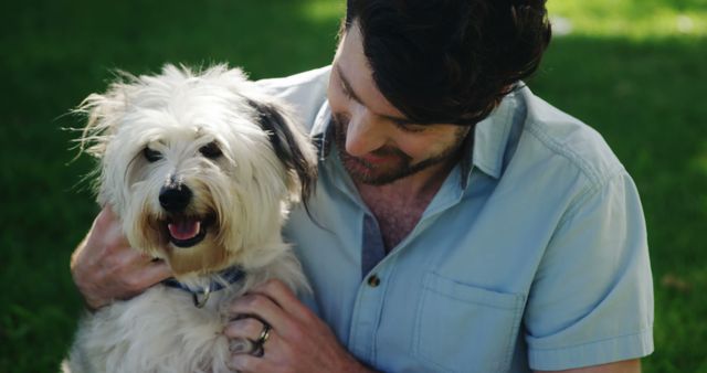 A middle-aged Caucasian man shares a joyful moment with his fluffy white dog in a sunlit park, with copy space. Their bond is evident as the man gently pets the dog, both relishing the outdoor companionship.