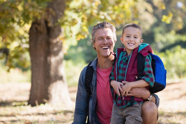 Portrait of happy mature father and elementary son in forest