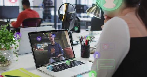 Remote presenter leading virtual meeting on laptop while coworker viewing in modern office