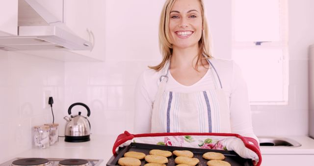Woman Smiling in Kitchen Holding Freshly Baked Cookies - Download Free Stock Images Pikwizard.com