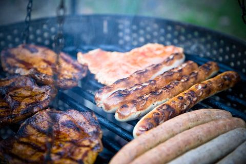 Grilling assorted sausages, chicken, and pork steaks with smoky char marks