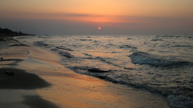 Serene Beach at Sunset with Gentle Waves and Orange Sky - Download Free Stock Photos Pikwizard.com