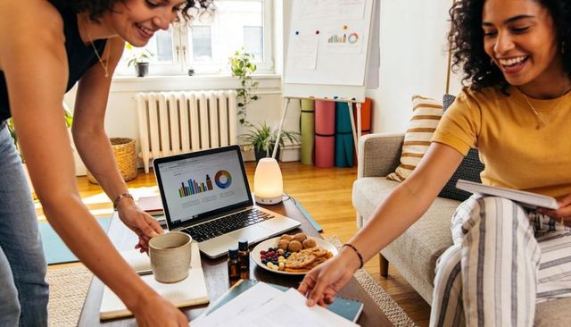 Collaborating women planning startup strategy in bright living room with laptop charts