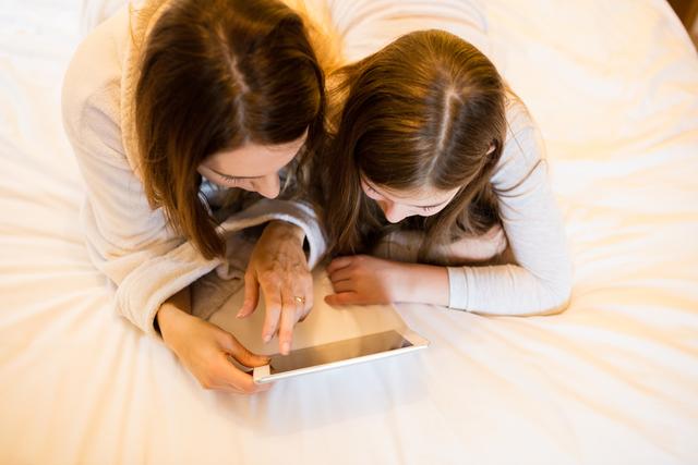 Mother and daughter using digital tablet in bedroom - Download Free Stock Photos Pikwizard.com