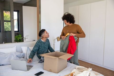 Two male roommates unpacking and organizing in modern bedroom