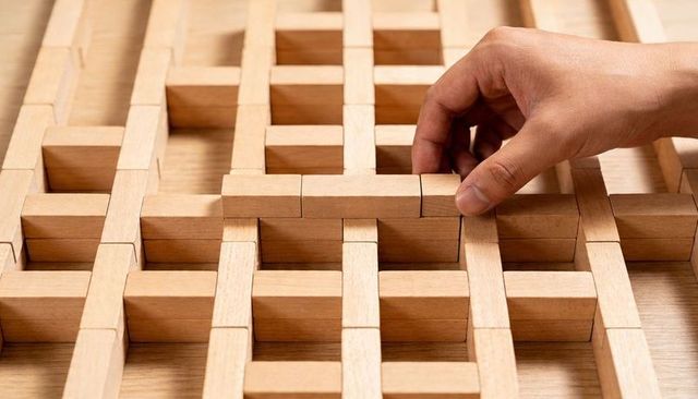 Hand Placing Wooden Block into Lattice Grid for Craft and Woodwork Closeup Detail