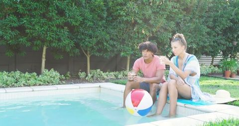 Couple relaxing poolside with beach ball in summertime