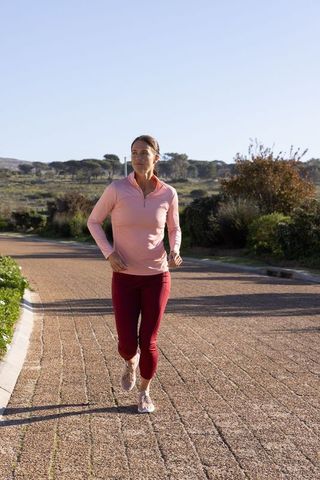Woman jogging on rural pathway surrounded by nature