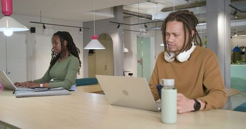 African american coworkers working at long communal table in modern coworking space