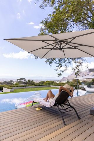 Woman lounging on deck chair by infinity pool with panoramic coastal view