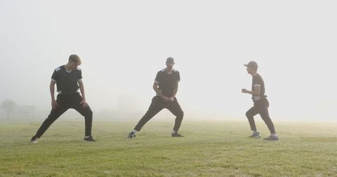Athletes Practicing Side Lunges on Foggy Sports Field