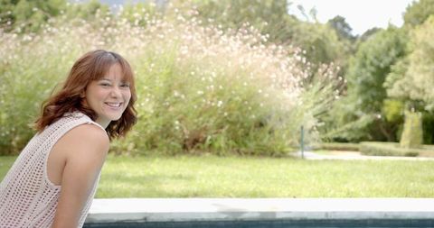 Smiling Woman Relaxing by Pool in Sunny Outdoor Setting