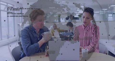 Two professionals collaborating at laptop with globe and code overlay in modern office