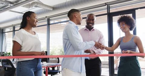 Team celebrating success with ribbon cutting in modern office