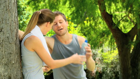 Couple Refreshing After Jogging in Park