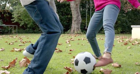 Mother and Son Playing Soccer Together in Lush Garden During Autumn