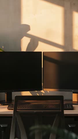 Vertical video casting window light and shadows across dual monitors on minimalist desk