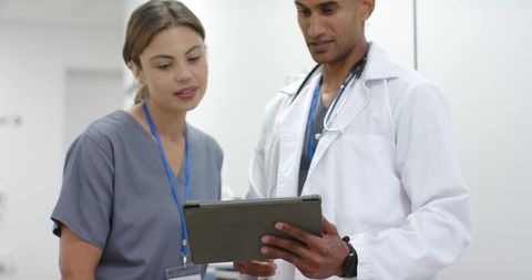 Doctor and african-american nurse reviewing tablet for digital patient care