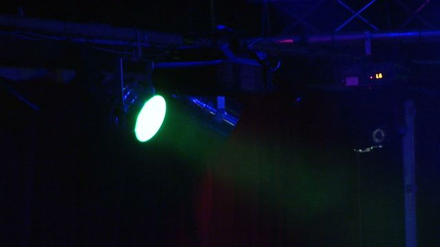 Close-up of a green spotlight illuminating a dark stage, perfect for themes related to nightlife, theater performances, live shows, stage design, and event lighting. Ideal for articles, promotional materials, blogs or flyers detailing events, stage setups, or design ideas.