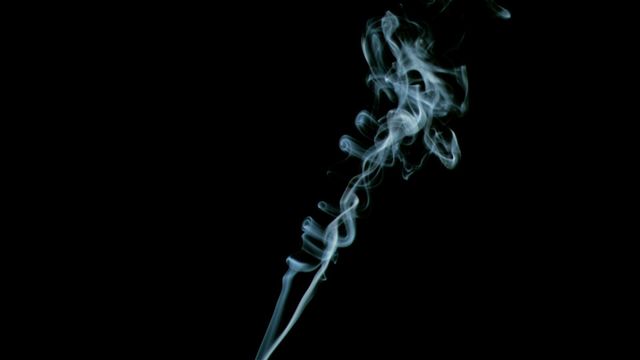 Plume of incense smoke curling gracefully against a black background. Ideal for meditation graphics, aromatherapy promotions, relaxation visuals, and tranquil settings where a sense of calm and serenity is needed. The flowing smoke creates an aesthetic appeal, perfect for backgrounds in spa ads or yoga studio posters.