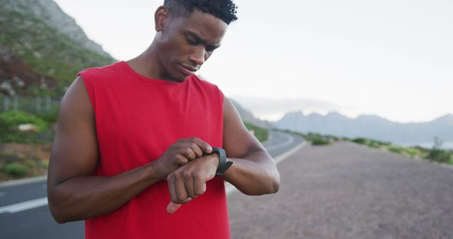 African american man using fitness band while standing on the road. fitness sports and healthy lifestyle concept