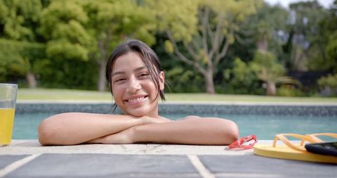 Smiling teenage girl relaxing at poolside on sunny day