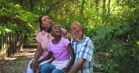 Grandparents Laughing with Granddaughter in Tranquil Park
