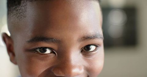 Closeup african boy gazing into camera smiling with bright eyes and soft bokeh