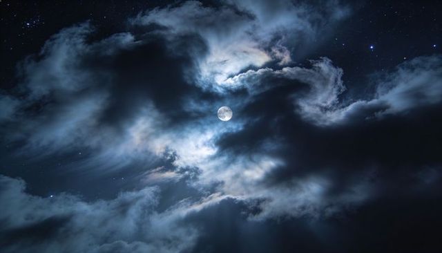 Full Moon Breaking Through Dramatic Layered Clouds with Silver Halo and Starry Night Sky