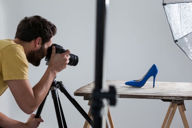 Male photographer photographing footwear in studio