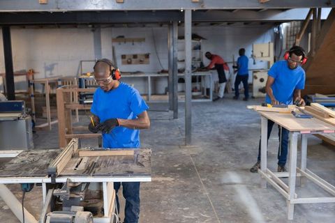 African American Men Working at Carpentry Workshop Measuring Marking Wood for Furniture