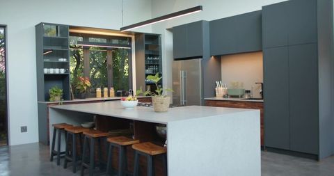 Modern Open-Plan Kitchen Featuring Stone Island, Wood Stools, Charcoal Cabinets