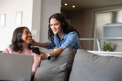 Diverse Female Friends Relaxing Together Using Devices at Home