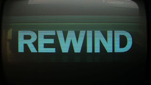 Vintage crt display showing rewind text glowing cyan with scanlines and bezel glare