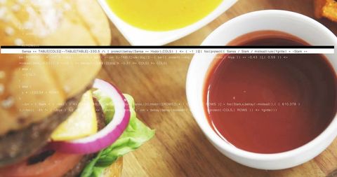 Close-up gourmet burger with red dipping sauce in ceramic bowl on wooden board with fries