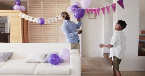Father and Son Decorating Purple Balloons for Home Birthday Celebration, Family Bonding