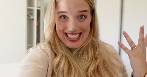 Excited young woman displaying stylish rings in modern interior