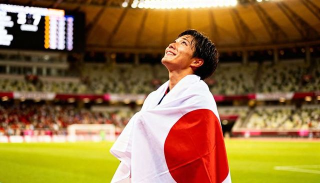Triumphant japanese athlete celebrating victory draped in flag under stadium lights