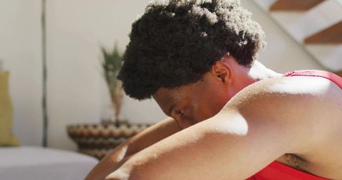 Man resting head on forearms, sunlit contemplative moment in minimalist living room