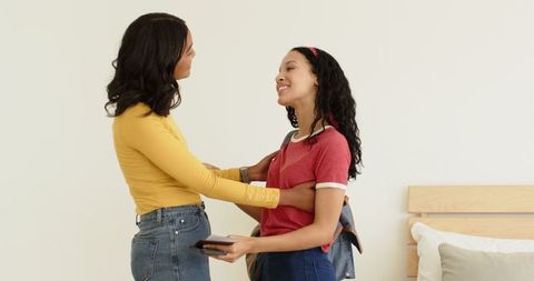 Warm Embrace Between Two Women at Home Holding Smartphone