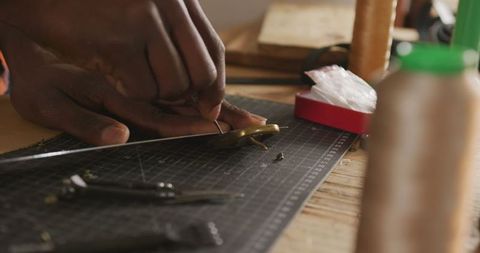 African american craftsman preparing leather belt in workshop